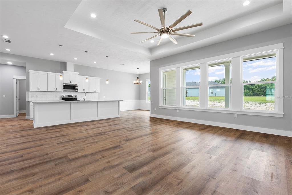 An open-concept kitchen and living area features white cabinetry, a large island, and wood flooring — 0 SW MEADOW VIEW COURT, LAKE CITY, FL
