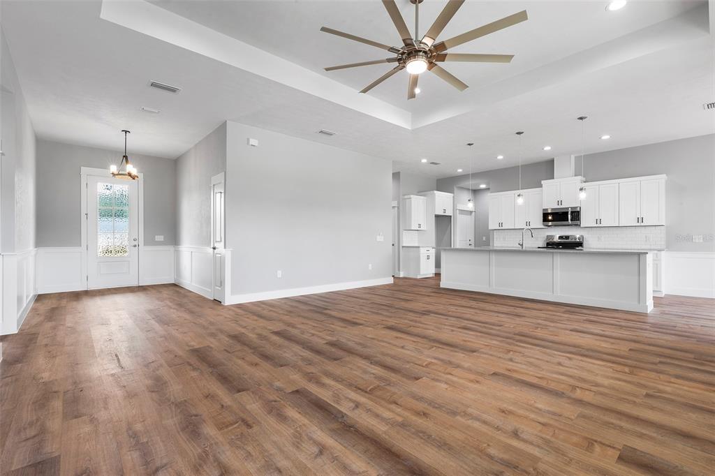 An open-concept living area features wood-look flooring, a tray ceiling with a fan, and kitchen — 0 SW MEADOW VIEW COURT, LAKE CITY, FL