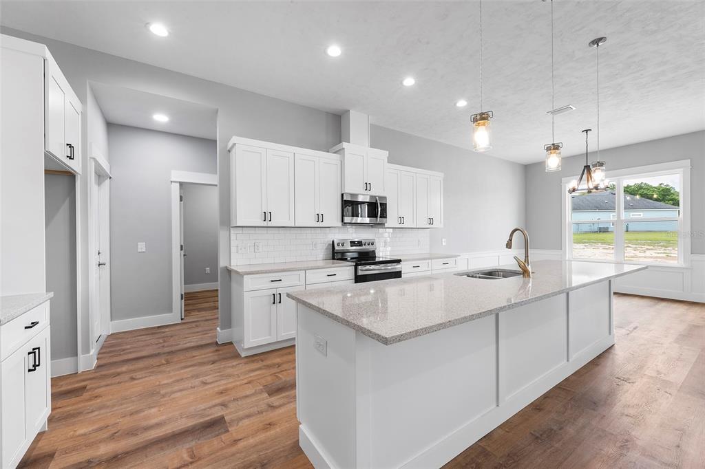 A modern kitchen features white cabinets, granite countertops, a large island, and wood-look flooring — 0 SW MEADOW VIEW COURT, LAKE CITY, FL