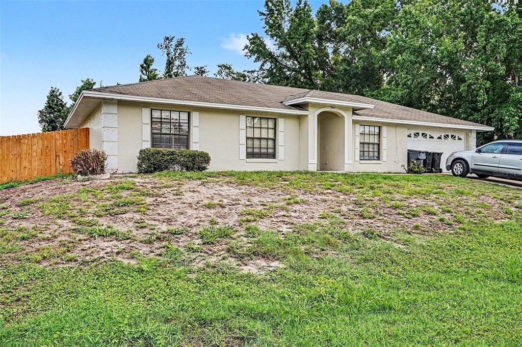 A single-story house with a beige exterior, a two-car garage, and a grassy front yard — 2435 PARKLAND DRIVE, LAKELAND, FL
