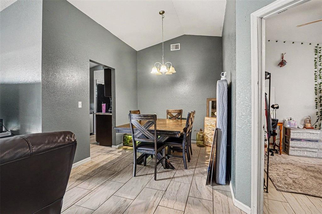 A dining room with a wooden table, chairs, and a chandelier under a vaulted ceiling — 2435 PARKLAND DRIVE, LAKELAND, FL