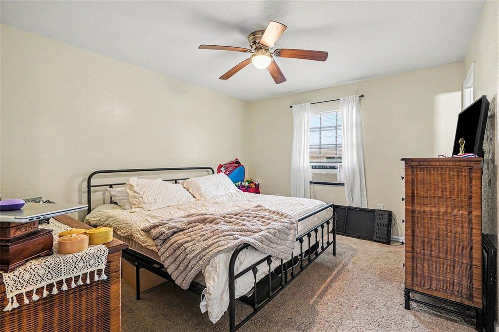 A bedroom features a metal-framed bed, a ceiling fan, and a wicker dresser — 2435 PARKLAND DRIVE, LAKELAND, FL