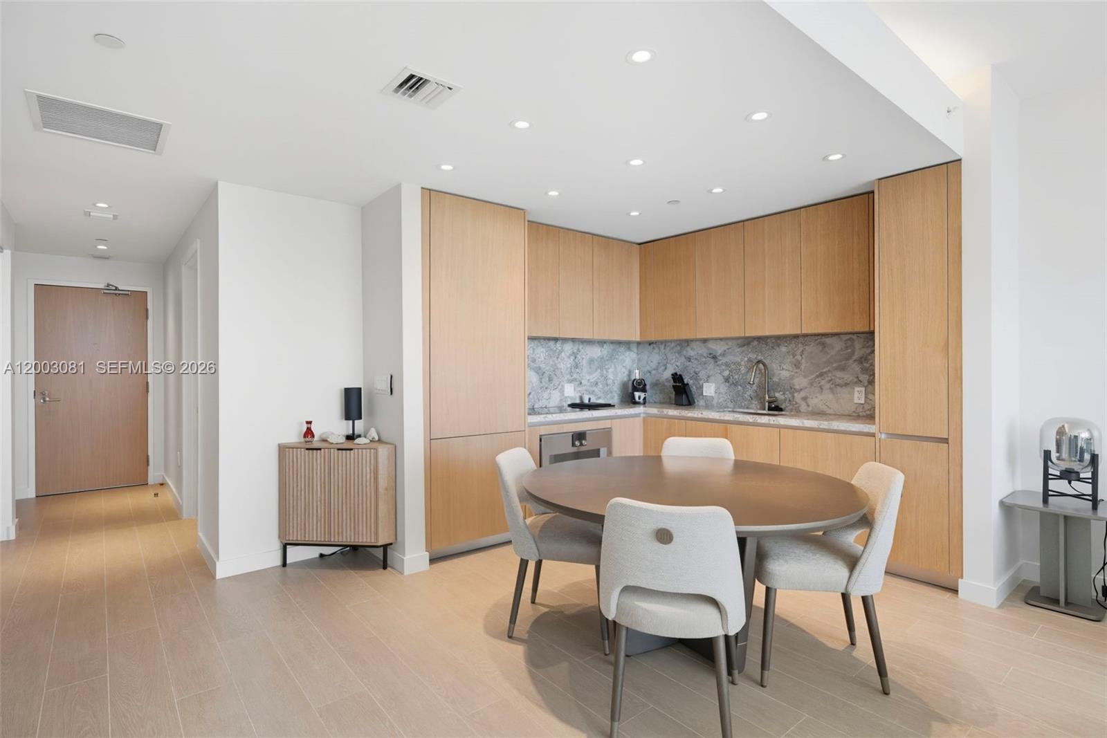 A kitchen and dining area features light wood cabinetry, a round table, and marble backsplash — 500 Alton Rd # 808, Miami Beach FL 33139, MIAMI BEACH, FL