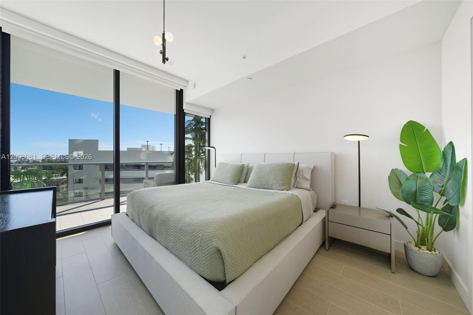 A modern bedroom features a bed with sage green bedding, a floor lamp, and balcony access — 500 Alton Rd # 808, Miami Beach FL 33139, MIAMI BEACH, FL