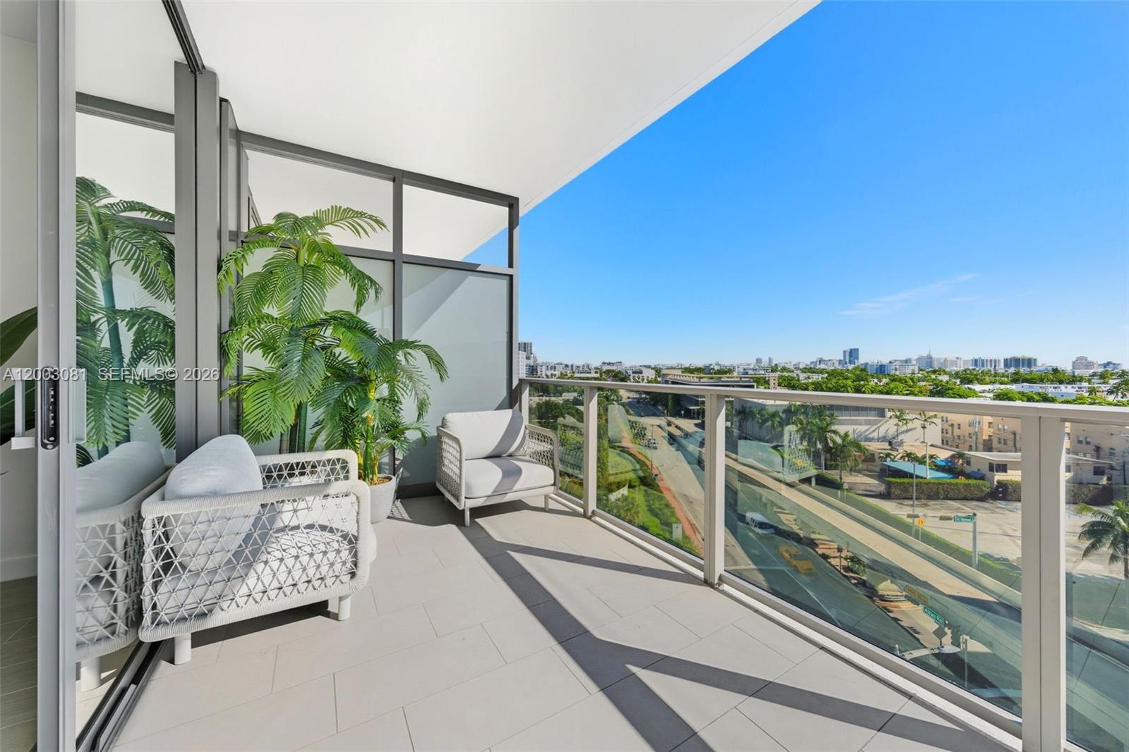 A modern balcony features two white chairs, a potted plant, and a glass railing — 500 Alton Rd # 808, Miami Beach FL 33139, MIAMI BEACH, FL