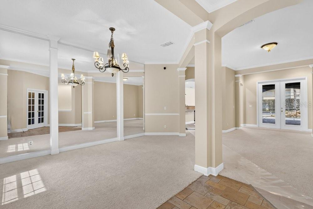 A carpeted room with mirrored walls, a chandelier, and French doors leading to the outside — 6658 VISTA PARK BOULEVARD, ORLANDO, FL