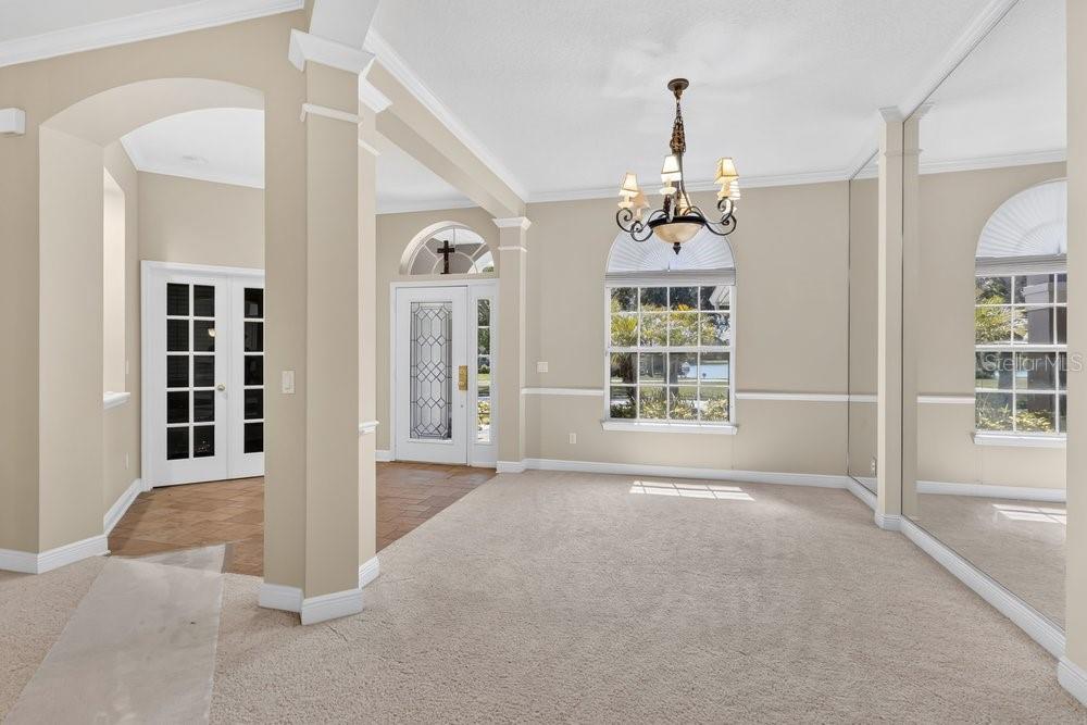 A carpeted dining room features a chandelier, arched windows, and a mirrored wall — 6658 VISTA PARK BOULEVARD, ORLANDO, FL