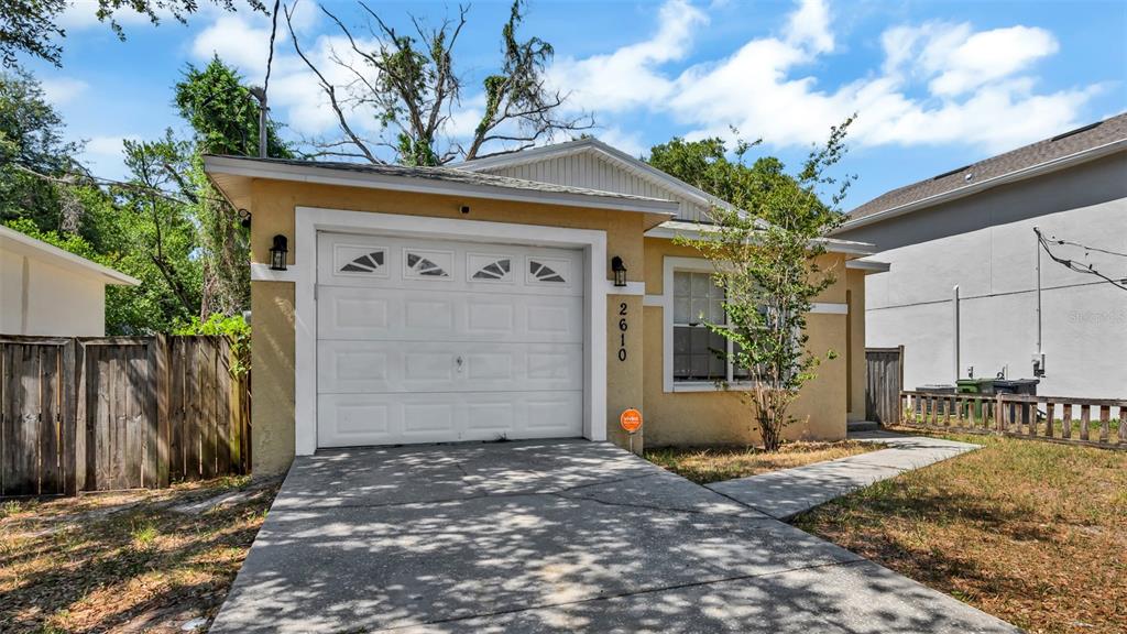 A single-story house with a yellow stucco exterior, a one-car garage, and a concrete driveway — 2610 E LAKE AVENUE, TAMPA, FL