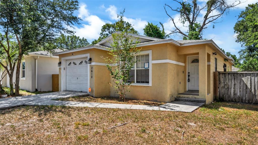 A single-story yellow house with a garage, front walkway, and a wooden fence — 2610 E LAKE AVENUE, TAMPA, FL