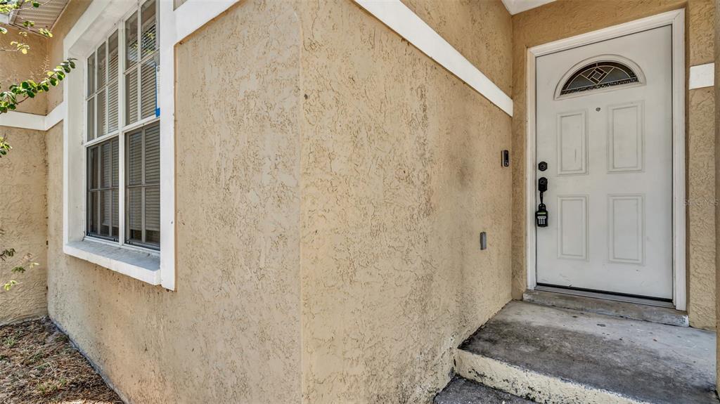 A beige stucco exterior wall features a white front door and a multi-pane window — 2610 E LAKE AVENUE, TAMPA, FL