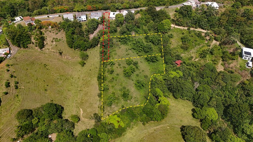 An aerial view shows a plot of land outlined in yellow and red on a hillside — Km 1.1 CARR 400, RINCON, PR