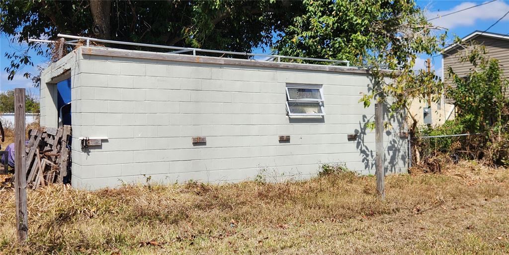 A rectangular concrete block shed with a metal roof rack stands in a grassy yard — 3457 GAINSBORO ROAD, PORT CHARLOTTE, FL