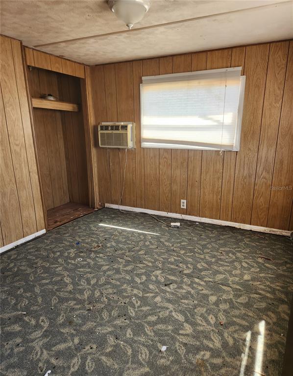A bedroom with wood-paneled walls, a window air conditioner, and a patterned carpeted floor — 3457 GAINSBORO ROAD, PORT CHARLOTTE, FL