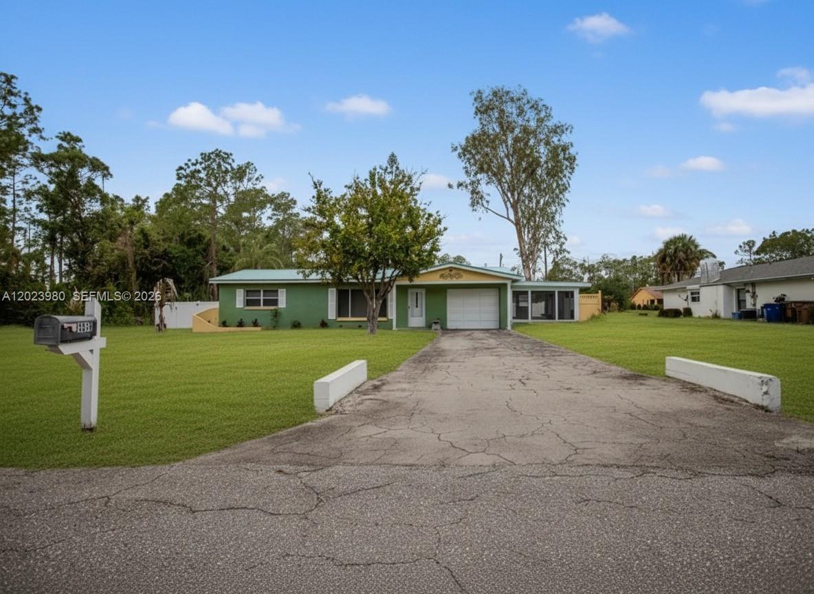 A single-story green house with a garage and a cracked concrete driveway — 1313 E CLEVELAND AVE, Lehigh Acres FL 33972, LEHIGH ACRES, FL