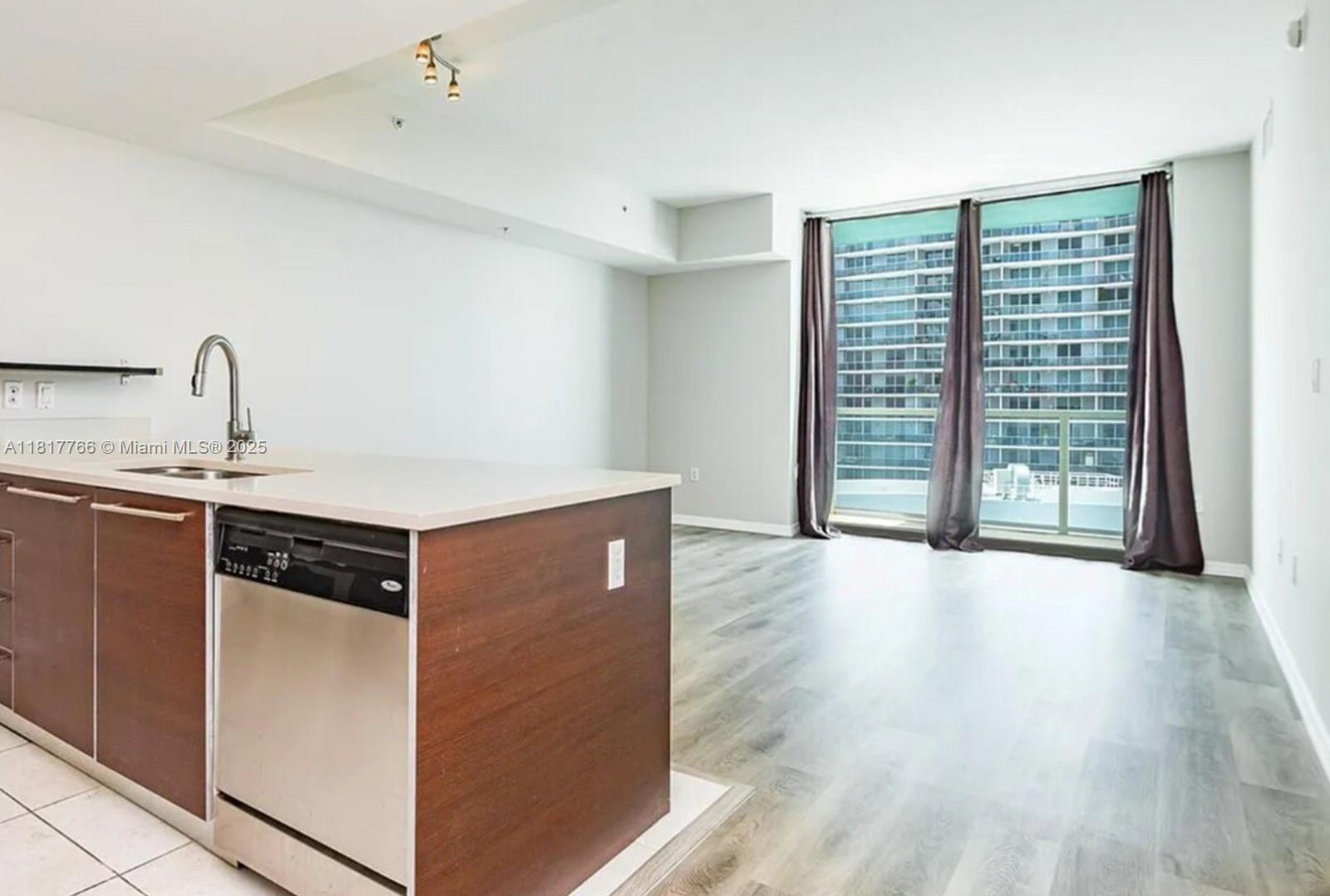 A kitchen island with a dishwasher faces an open living area with floor-to-ceiling windows — 1900 N Bayshore Dr # 3909, Miami FL 33132, MIAMI, FL