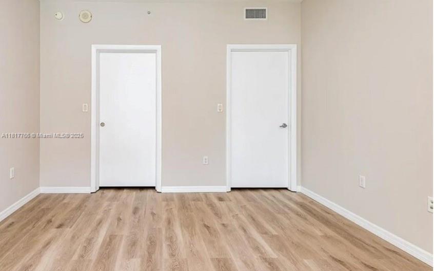 An empty room features light wood-look flooring, beige walls, and two white interior doors — 1900 N Bayshore Dr # 3909, Miami FL 33132, MIAMI, FL