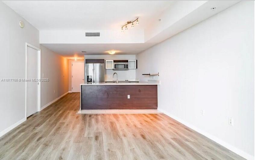 An open-concept kitchen with a dark wood island, stainless steel appliances, and light wood flooring — 1900 N Bayshore Dr # 3909, Miami FL 33132, MIAMI, FL