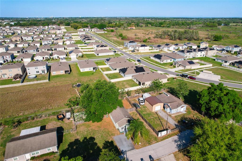 An aerial view shows a residential neighborhood with houses, yards, and surrounding undeveloped land — 213 CLEVELAND AVENUE, WINTER HAVEN, FL
