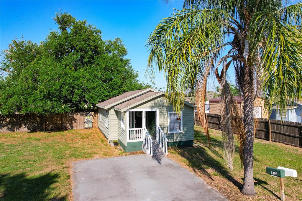 A small, light green house with a front porch stands on a grassy lot — 213 CLEVELAND AVENUE, WINTER HAVEN, FL