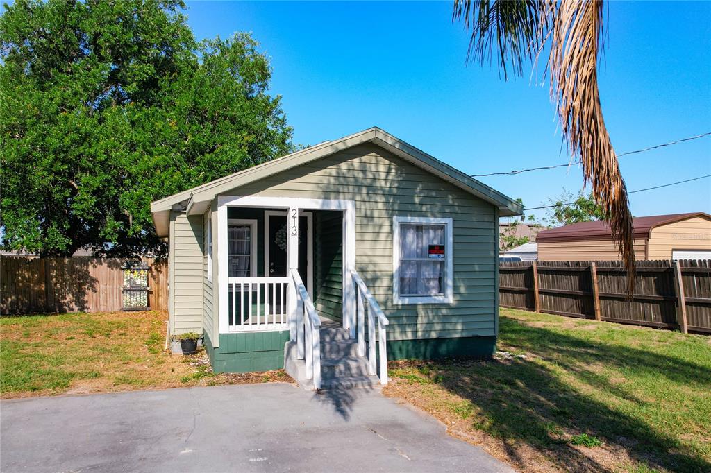 A small, light green, single-story house with a front porch and white railings — 213 CLEVELAND AVENUE, WINTER HAVEN, FL