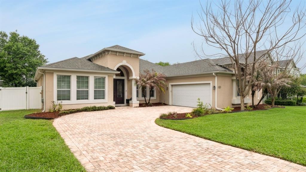 A single-story house with a beige stucco exterior, a paver driveway, and a two-car garage — 2028 MISTY GLEN DRIVE, APOPKA, FL