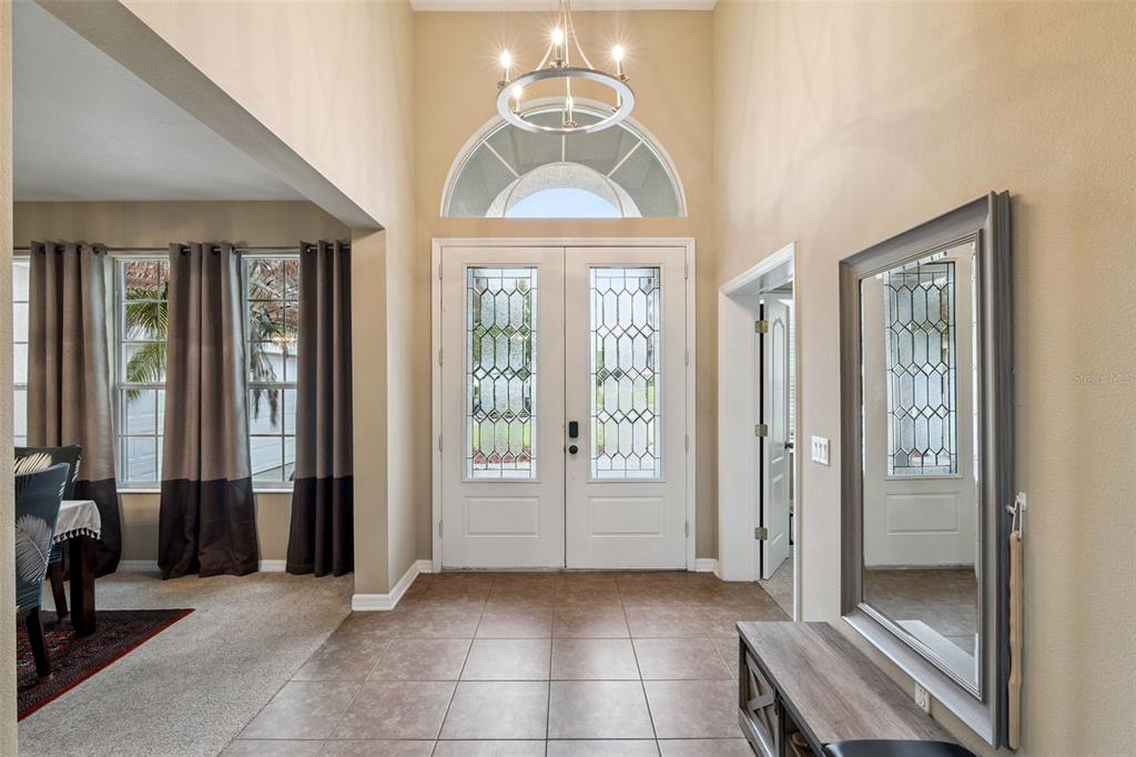 A bright entryway features tiled floors, a double front door, and a large wall mirror — 2028 MISTY GLEN DRIVE, APOPKA, FL