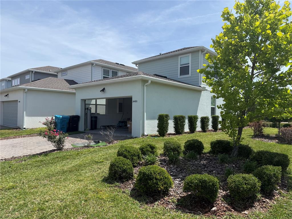A two-story house with a light-colored exterior, an open garage, and a landscaped front yard — 14486 SAPELO BEACH DRIVE, ORLANDO, FL