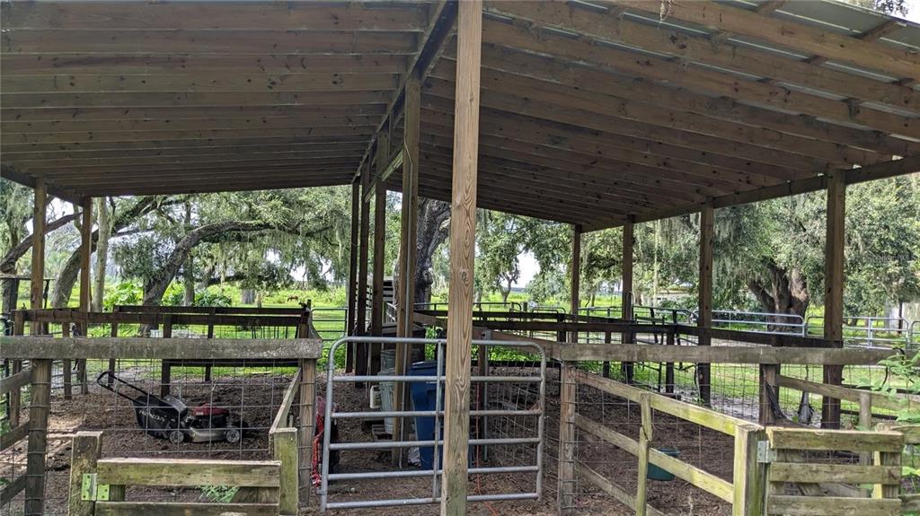 A covered outdoor animal pen or stable with wooden posts and wire fencing — 12980 and 12990 RIVER ROAD, MYAKKA CITY, FL