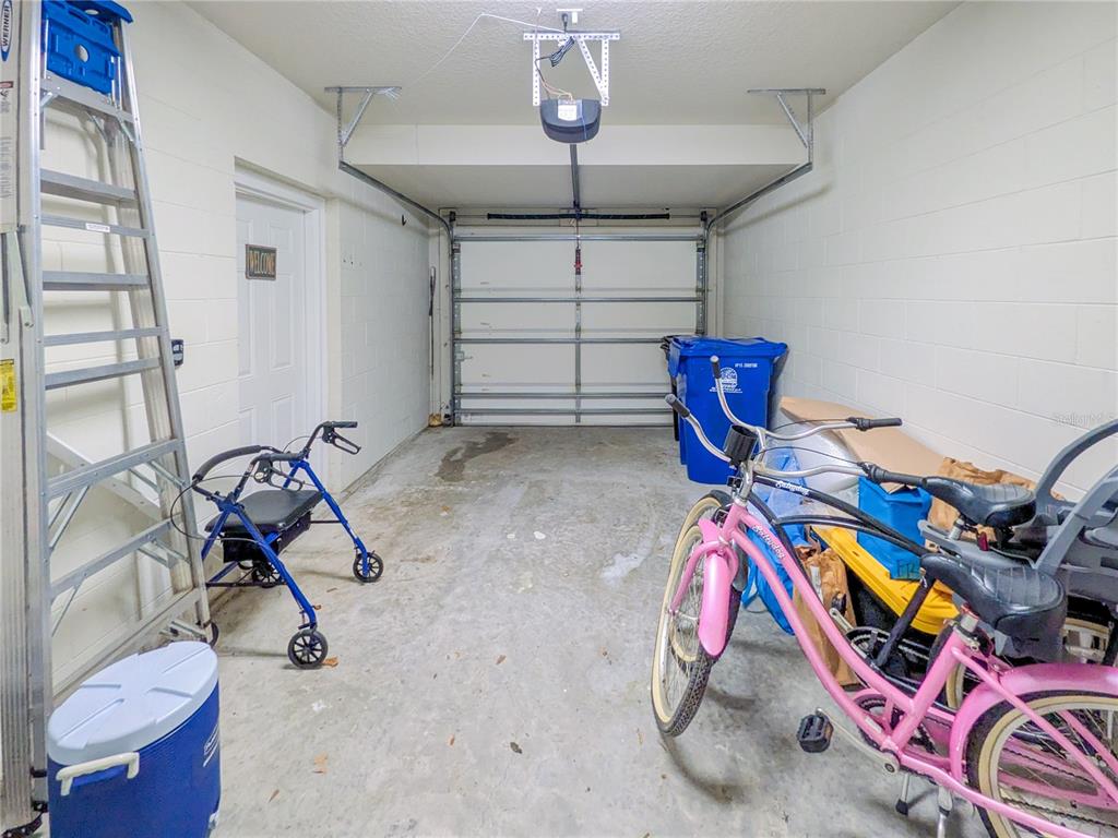 A one-car garage with a concrete floor, white block walls, and various stored items — 43 FAWN GULLY LANE UNIT F, PONTE VEDRA, FL