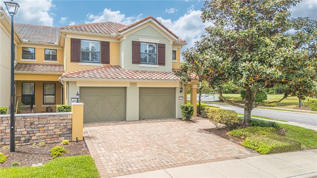 A two-story townhouse with a two-car garage, stone wall, and paver driveway — 43 FAWN GULLY LANE UNIT F, PONTE VEDRA, FL