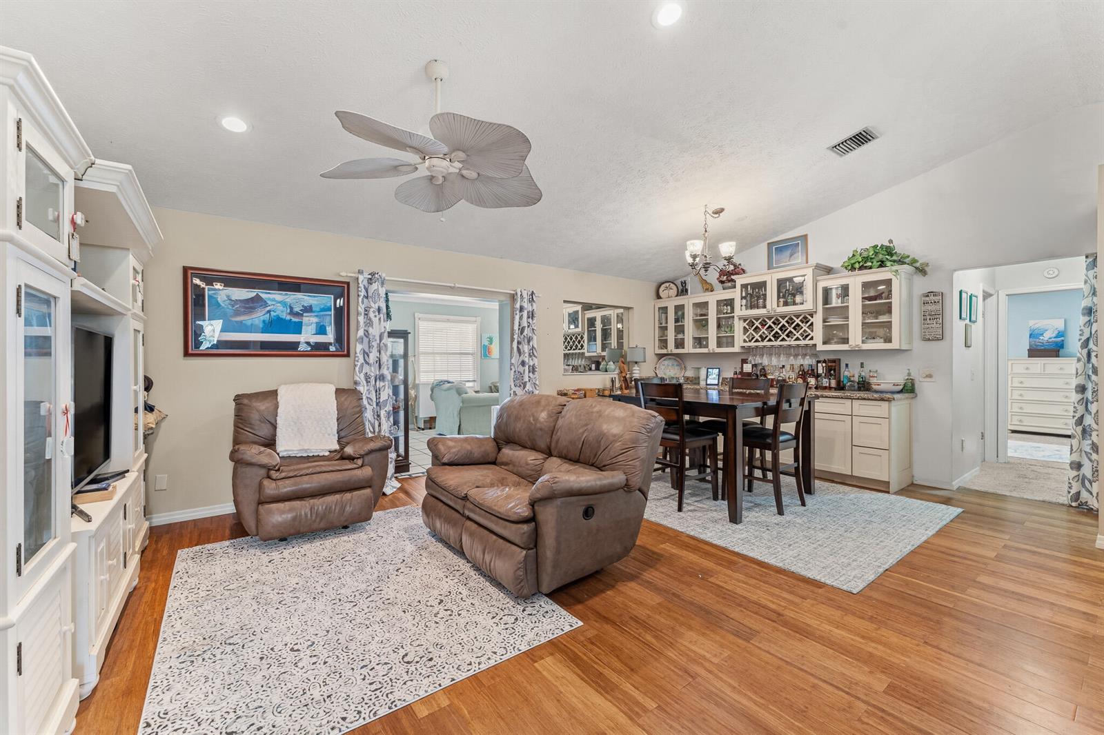 A living room and dining area with brown leather furniture, wood floors, and white cabinetry — 4459 SE Kubin Avenue, Stuart FL 34997, STUART, FL