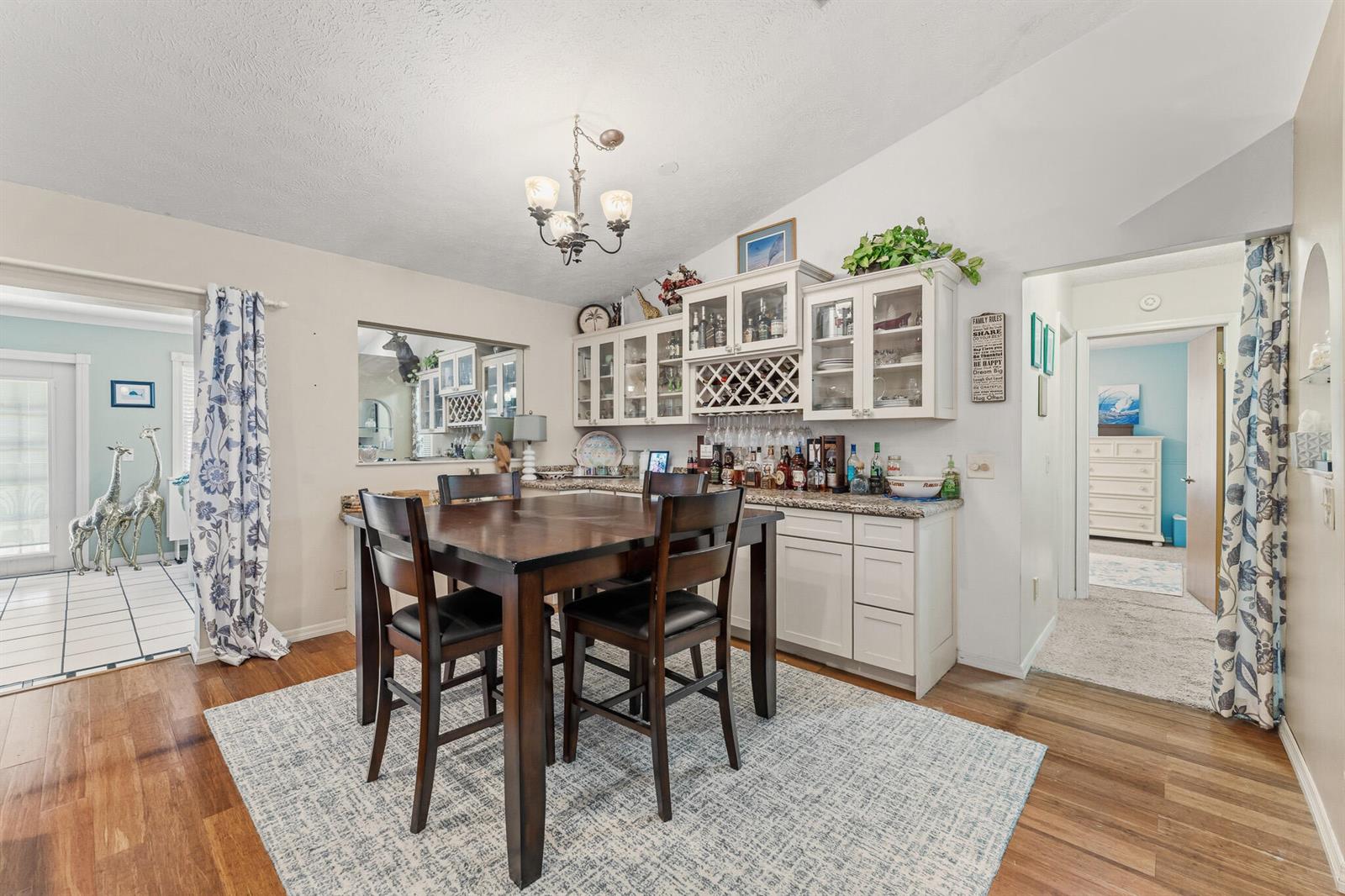 A dining area features a dark wood table, chairs, a built-in bar, and hardwood floors — 4459 SE Kubin Avenue, Stuart FL 34997, STUART, FL