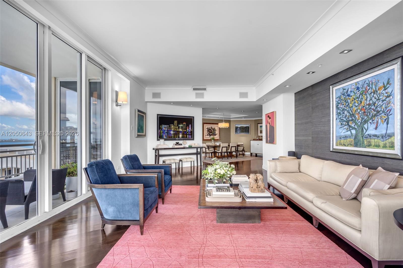 A living room features a pink rug, blue armchairs, a beige sofa, and balcony views — 848 Brickell Key Drive, Miami FL 33131, MIAMI, FL