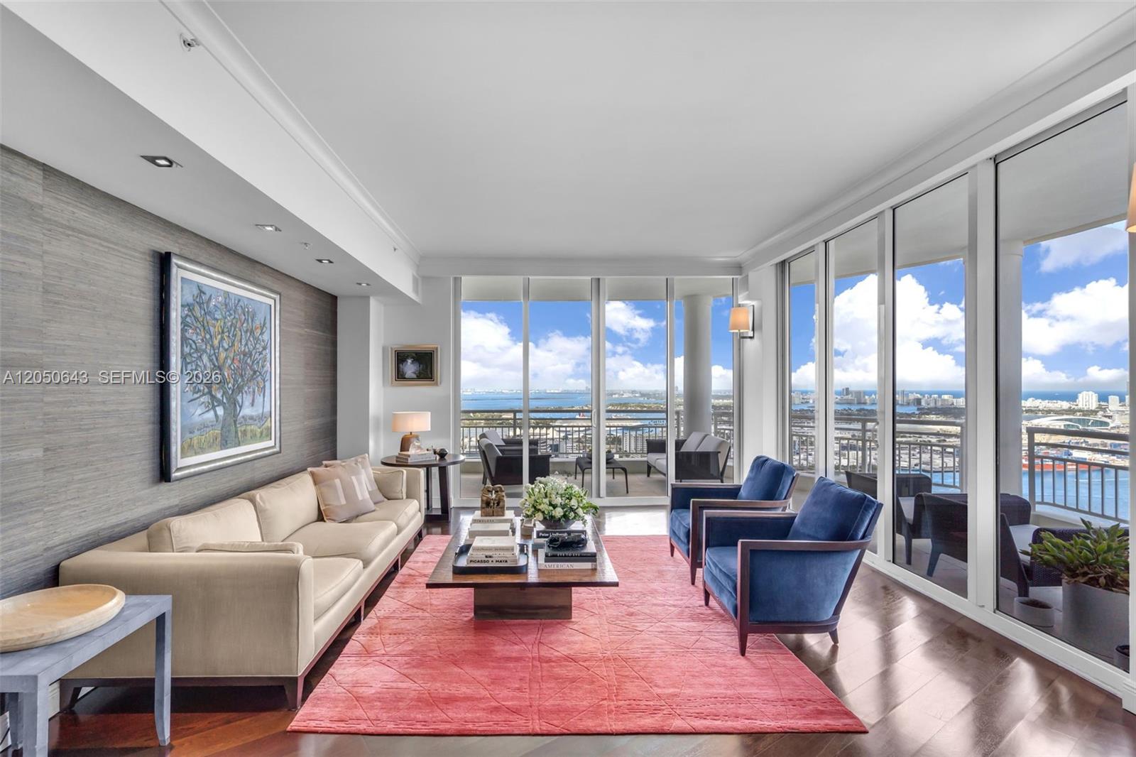 A living room features a beige sofa, blue armchairs, a pink rug, and floor-to-ceiling windows — 848 Brickell Key Drive, Miami FL 33131, MIAMI, FL