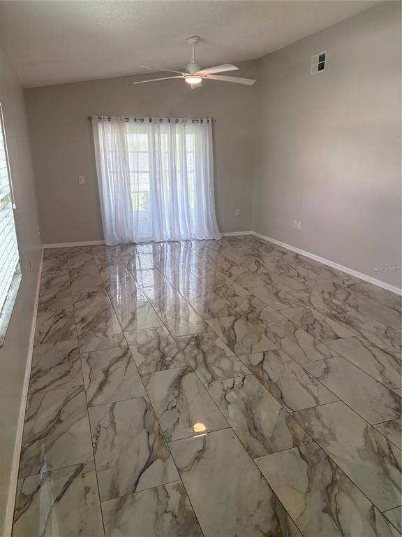 A room with light gray walls, a ceiling fan, and polished marble-look tile flooring — 9221 ESTRADA PLACE, NEW PORT RICHEY, FL
