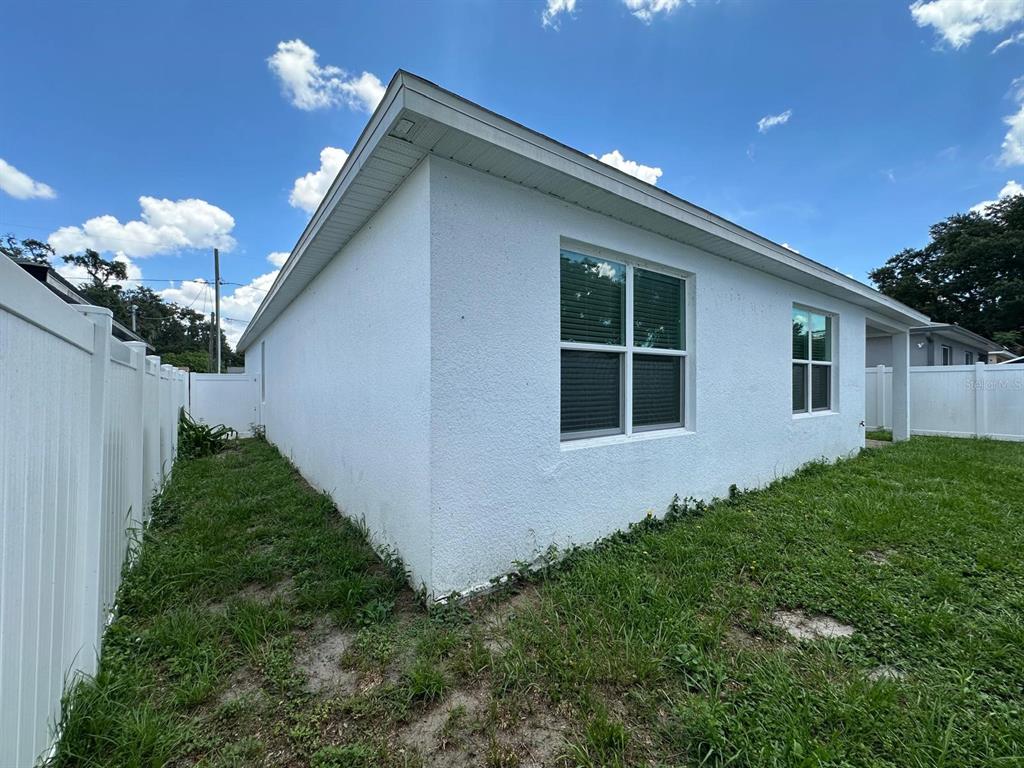 The exterior of a white stucco house features two windows and a white vinyl fence — 117 W MURPHY STREET, DAVENPORT, FL