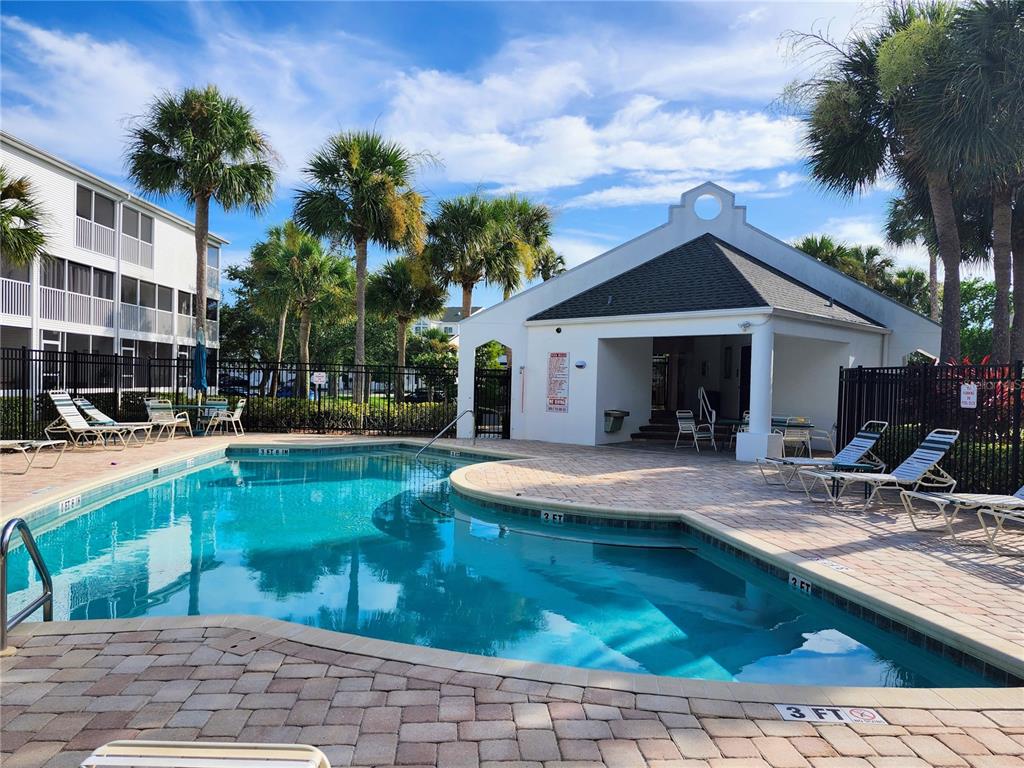 A swimming pool with a surrounding patio and a clubhouse building under a blue sky — 14883 SEMINOLE TRAIL UNIT 130, SEMINOLE, FL