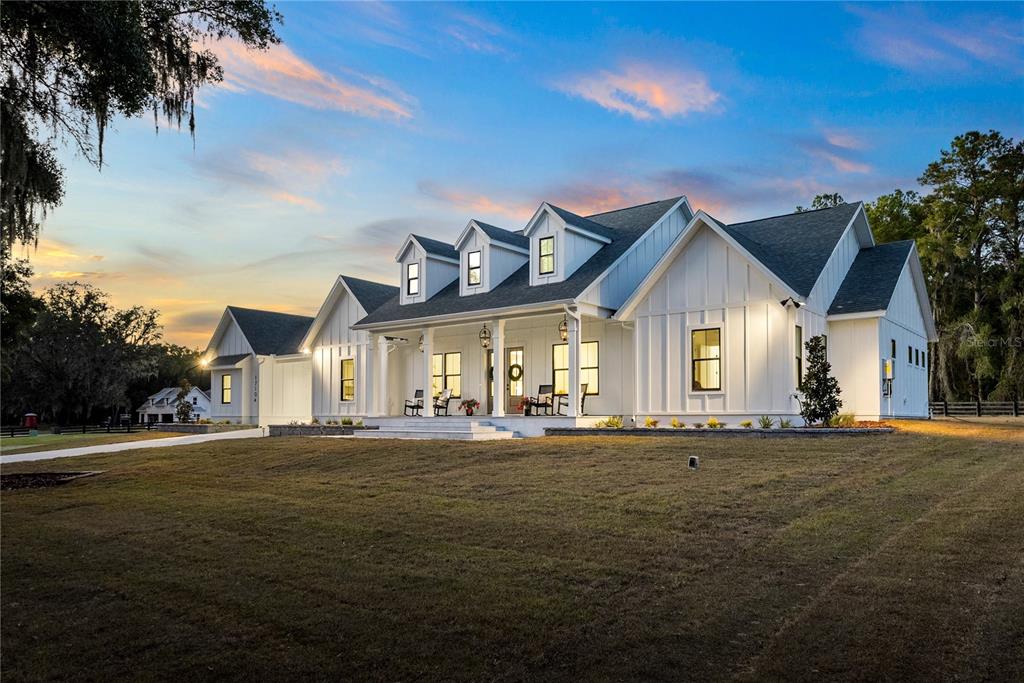 A white farmhouse with a metal roof and three dormers sits on a grassy lot — 17104 SW 11TH COURT, NEWBERRY, FL