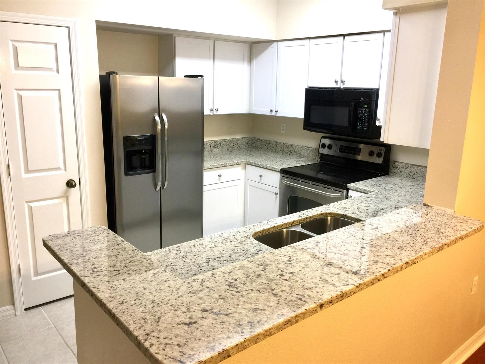 A kitchen with white cabinets, granite countertops, stainless steel appliances, and a breakfast bar — 10000 SW 52nd Avenue # 76, Gainesville FL 32608, GAINESVILLE, FL