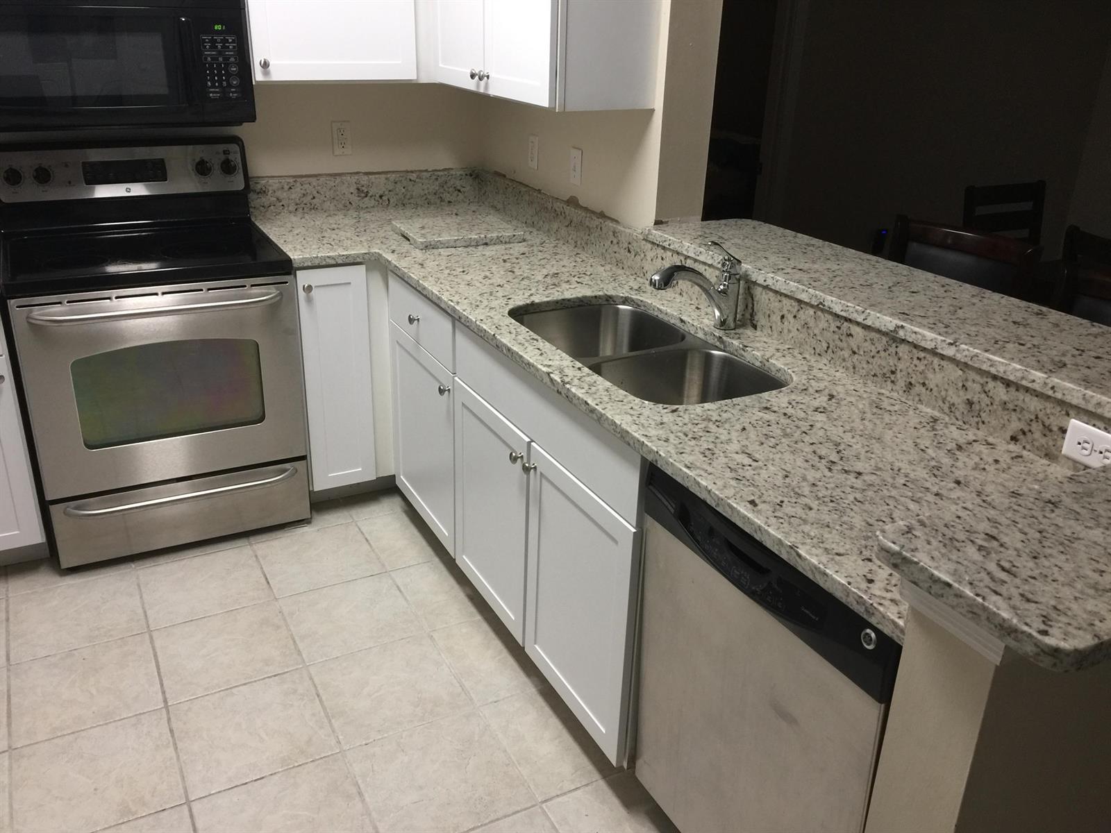 A kitchen features white cabinets, granite countertops, stainless steel appliances, and a double-basin sink — 10000 SW 52nd Avenue # 76, Gainesville FL 32608, GAINESVILLE, FL