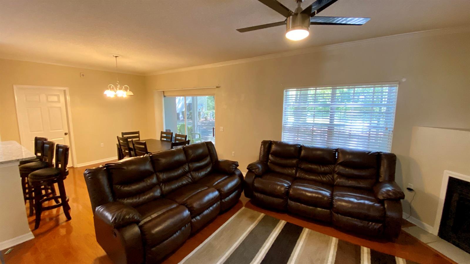 A living room with two brown leather sofas, a ceiling fan, and a dining area — 10000 SW 52nd Avenue # 76, Gainesville FL 32608, GAINESVILLE, FL