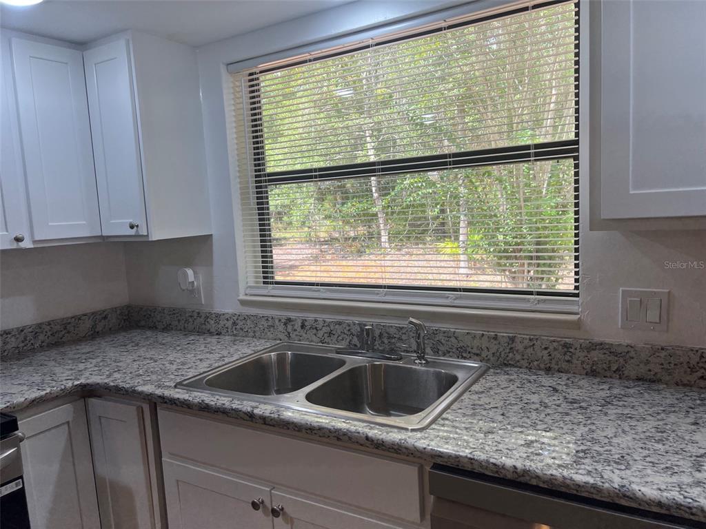 A kitchen features white cabinets, granite countertops, a double-basin sink, and a window with blinds — 9700 SW 209TH COURT, DUNNELLON, FL