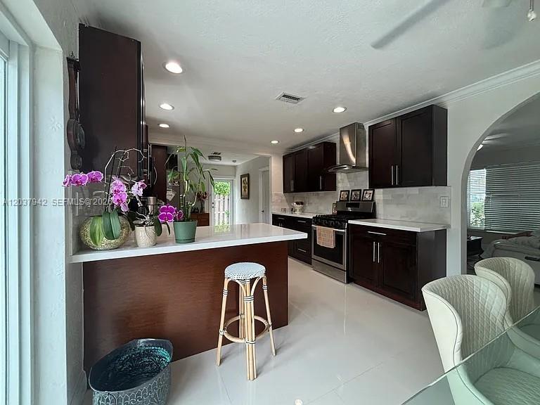 A kitchen features dark wood cabinets, white countertops, a breakfast bar, and stainless steel appliances — 12500 SW 104th Ter, Miami FL 33186, MIAMI, FL