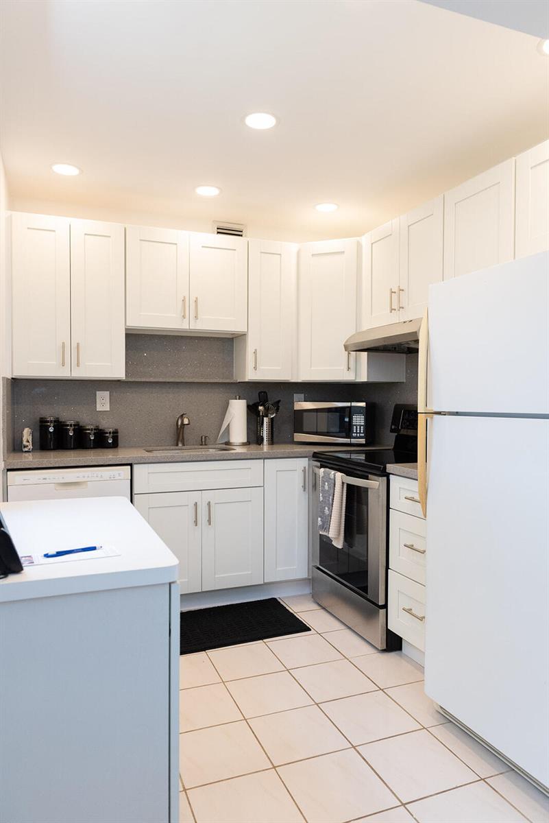 A kitchen features white cabinets, stainless steel appliances, a gray countertop, and tiled flooring — 416 Capri I, Delray Beach FL 33484, DELRAY BEACH, FL