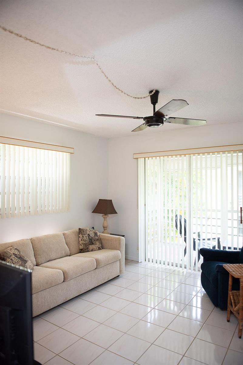A living room features a beige sofa, a dark armchair, tile flooring, and a ceiling fan — 416 Capri I, Delray Beach FL 33484, DELRAY BEACH, FL