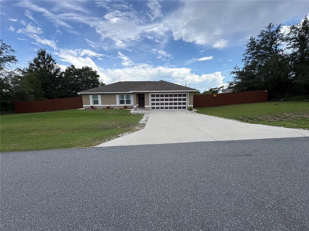 A single-story house with a tan exterior, a two-car garage, and a brown privacy fence — 176 JUNIPER LOOP CIRCLE, OCALA, FL