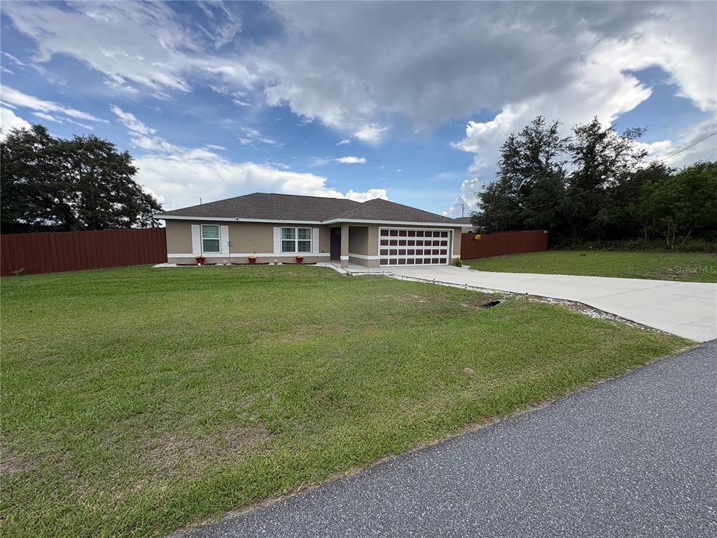 A single-story house with a tan exterior, a two-car garage, and a red privacy fence — 176 JUNIPER LOOP CIRCLE, OCALA, FL