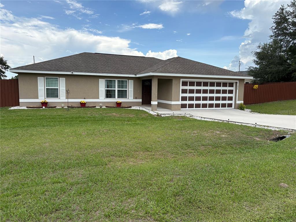 A single-story house with a tan exterior, brown roof, and a two-car garage — 176 JUNIPER LOOP CIRCLE, OCALA, FL