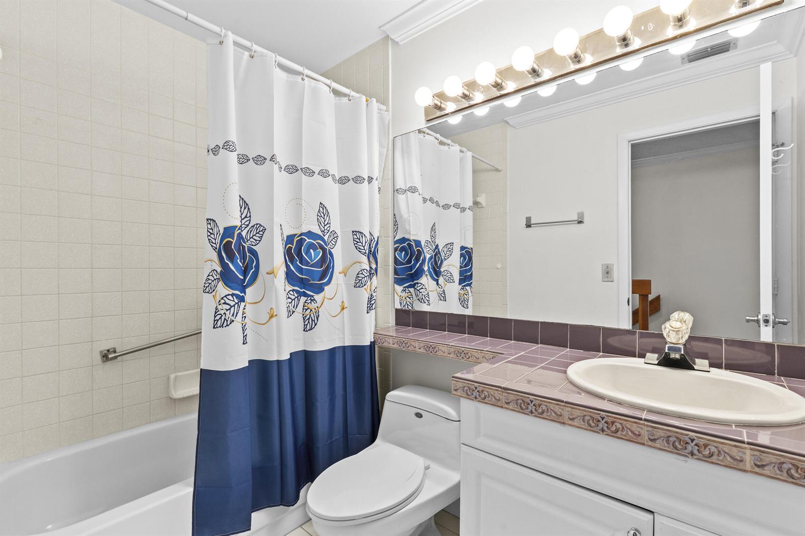A bathroom features a white vanity with purple tile countertops, a toilet, and a shower-tub combo — 218 Foxtail Drive # B, FL 33415, FL