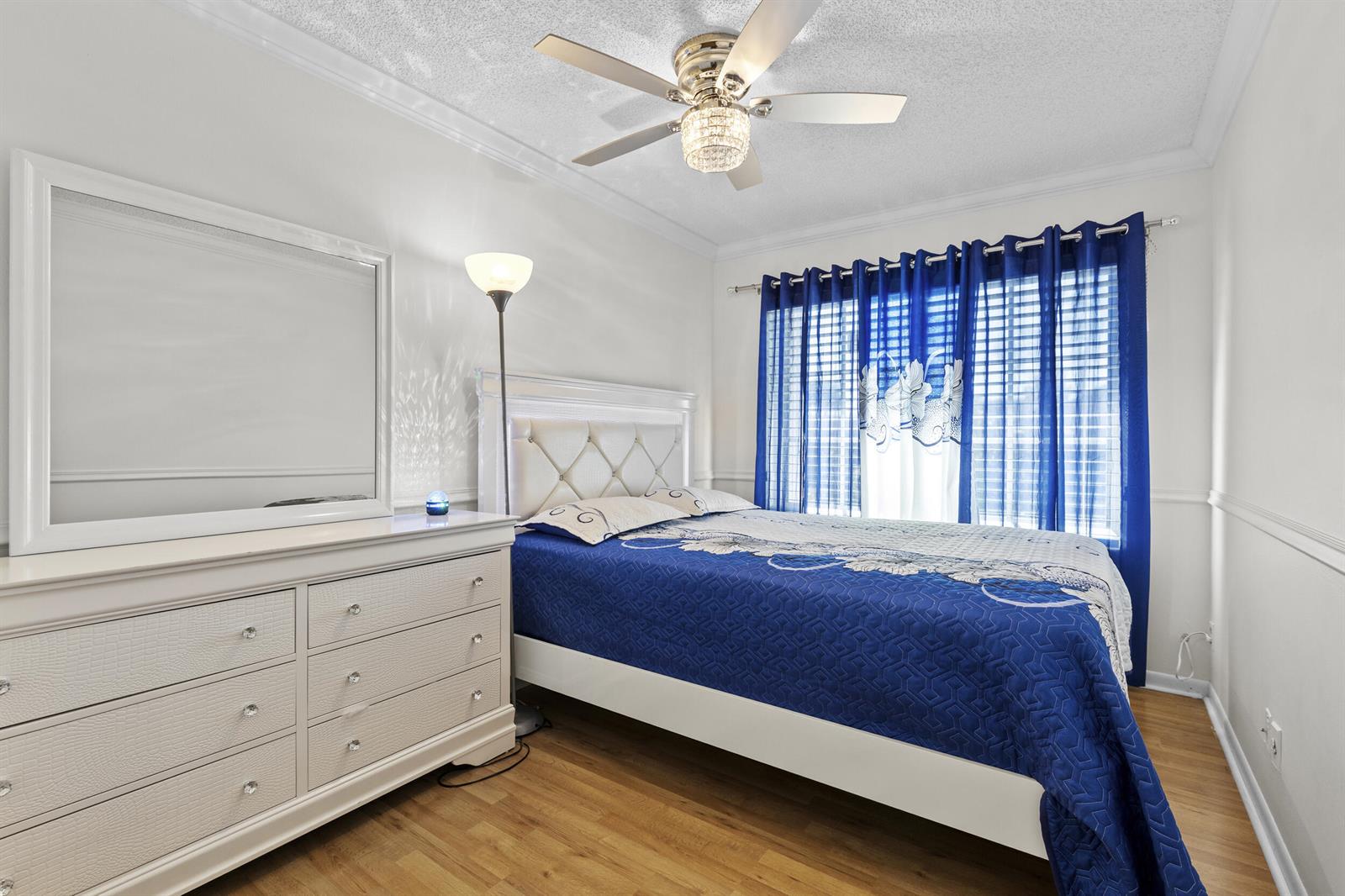 A bedroom features a white dresser, a bed with a blue quilt, and blue curtains — 218 Foxtail Drive # B, FL 33415, FL